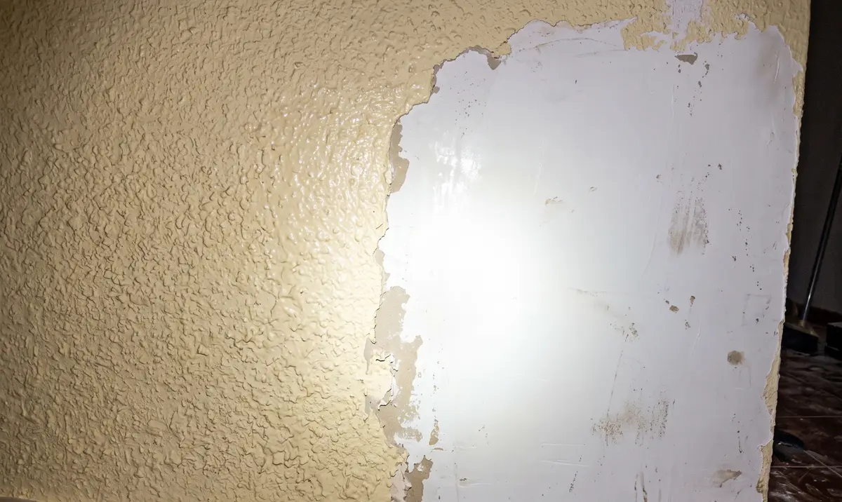 Rodapié y suelo protegidos con cinta y plástico durante el alisado de una pared